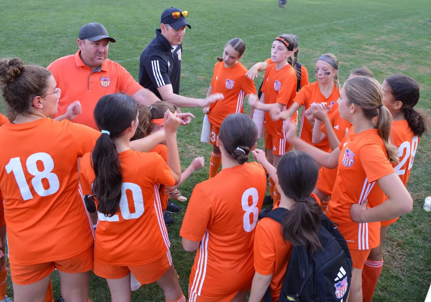 Coaches and a Rebels girls team huddled together after a win