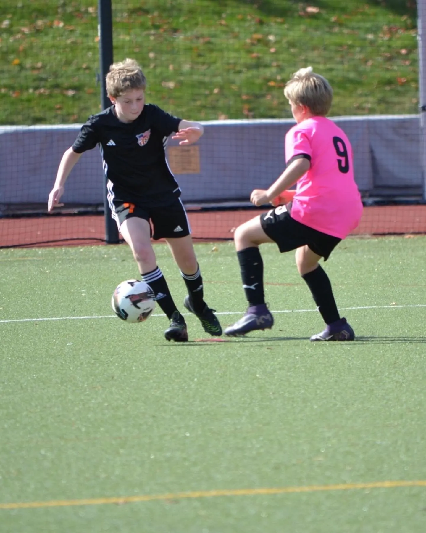 A Rebels player in black dribbling the ball past an opponent