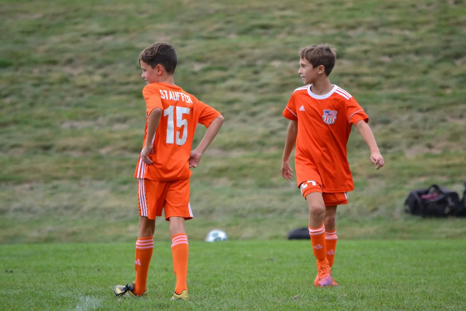 Two Rebels players in orange kits on the field during a game