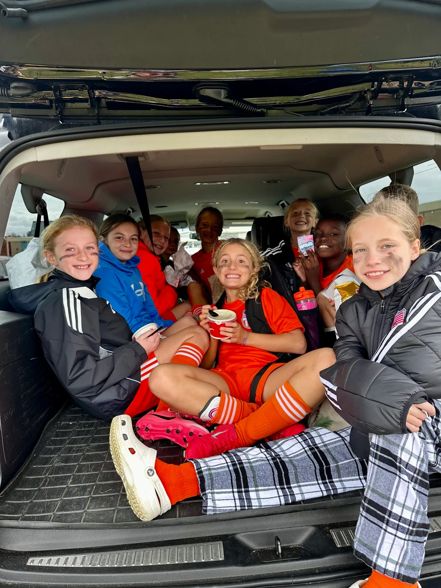 A Rebels team crowded into the back of a car with snacks after a game